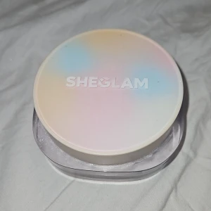 SHEGLAM Radiance Ring Setting Powder - SHEGLAM Radiance Ring 3-in-1 correcting setting powder i en rund burk med pastellfärgat lock. Innehåller tre olika nyanser i puderform för att ljusa upp, korrigera och fixera makeup. Perfekt för en fräsch och jämn finish.