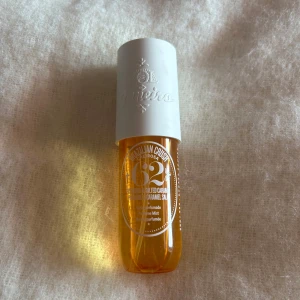 Sol de Janeiro 62 Parfymmist -  62 från Sol de Janeiro är en ikonisk parfymmist med doft av pistage och saltad karamell. Flaskan är genomskinlig orange med vit kork och rymmer 90 ml. Perfekt för dig som älskar söta, tropiska dofter och vill ha en fräsch vibe. Ändast testad!
