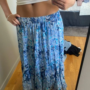 Blå mönstrad långkjol med resår - Säljer en jätte söt lågmidjad flowy långkjol med blått och vitt abstrakt mönster. Kjolen har resår i midjan och är stretchig och gjord i ett lätt, svalt tyg som passar perfekt till varma dagar. 