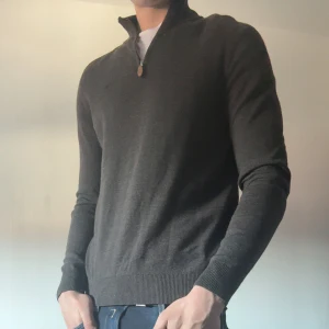 Brun merinoullströja från Morris - Snygg brun stickad tröja från Morris i 100% merinoull. Tröjan har half zip med läderdetalj vid dragkedjan, ribbade muddar och lång ärm. Perfekt för dig som gillar stilren och klassisk look med en modern touch.Nypris 1800 mitt pris 400