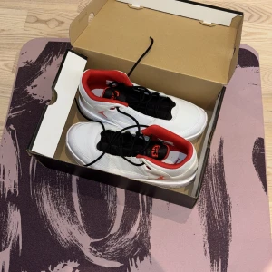 Nike Air Jordan sneakers vit/röd - Snygga Nike Air Jordan sneakers i vitt skinn med svarta detaljer och röd insida. Klassisk Jumpman-logga på sidan och 23-detalj på plösen. Skorna har snörning och en chunky sula med synlig air-enhet i hälen. Perfekta för dig som gillar streetstyle.