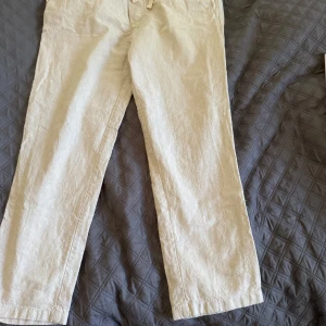 Beiga linnebyxor med snörning från Zara - Snygga beiga linnebyxor från Zara i storlek L. Byxorna har elastisk midja med snörning och raka ben. Perfekta för chill dagar eller när du vill ha en avslappnad men stilren look. Lätta och luftiga i materialet, med fickor både fram och bak.