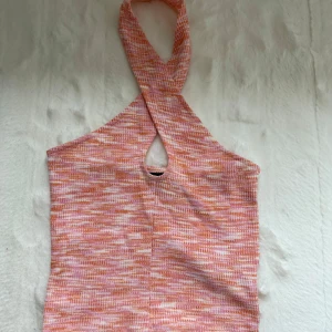 Rosa/orange halterneck topp - Säljer en ribbad halterneck topp i rosa och orange toner med korsad hals och liten cut-out framtill. Från Ginatricot. Om du önskar fler bilder, skicka dm!🩷