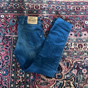 Blå Replay jeans med raka ben - Säljer ett par klassiska blå jeans från Replay med raka ben. Jeansen har fem fickor, normal midja och tydlig Replay-logga på bakfickan samt läderpatch i midjan. Perfekta för dig som gillar en tidlös och avslappnad look.