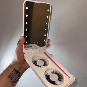 Fransbox med LEDljus och lösögonfransar - Snygg sminkspegel med LED-belysning i vit plast, perfekt för att fixa sminket. Medföljer två par svarta, fluffiga lösögonfransar och en rosa svarteyeliner som även är lim. Allt kommer i ett praktiskt fodral som är lätt att ta med sig.