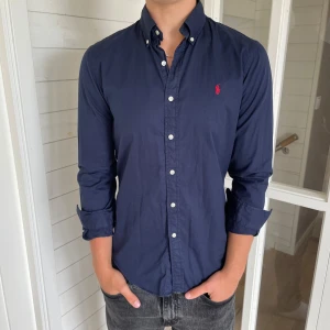 Polo Ralph lauren skjorta - Säljer denna riktigt snygga mörkblåa Ralph lauren skjorta, den är i mycket bra skick utan några defekter, Storlek M modell slim fit den är 75 cm lång och 47 cm bred under armhålorna, hör gärna av dig vid frågor!