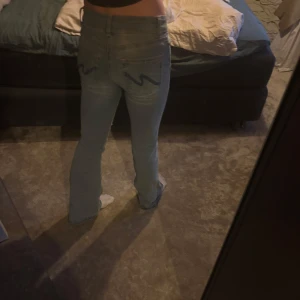 Bootcut jeans från Nelly ljusblå - Säljer ett par ljusblå bootcut jeans från Nelly i storlek 34. Jeansen har klassisk femficksdesign, normal passform upptill och utsvängda ben. Materialet är mjukt denim och de har snygga sömmar på bakfickorna.det rosa är uppsprätt och är lite frasiga. Dem är helt unika då det är gjort själv.derföe lägre pris  Dem är även uppsprätta i längden. 