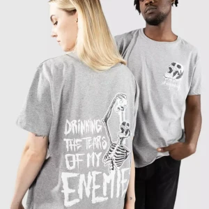 Grå t-shirt Blue Tomato med skelettprint - Grå t-shirt från Blue Tomato med stort tryck på ryggen av ett skelett och texten 'Drinking the tears of my enemies'. Framsidan har en dödskalle och texten 'Any Means Necessary'. Skön passform och cool design, perfekt för dig som gillar edgy streetwear.