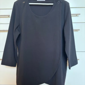 Rodebjer Bea Blazer storlek L - Rodebjers klassiska Bea Blazer storlek L, med trekvartsärm och rund halsringning. Kavajen omlott-design med knappar på axlarna. Lika snygg stängd som öppen. Så användbar!