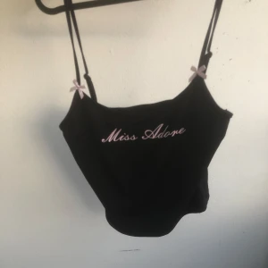 Svart linne jätte gullig - Gullig svart linne med tunna axelband som går att justera och små ljusrosa rosetter vid banden. Den är storlek S men den är stretch i så den passar XS till M. Tycker den är jätte söt men aldrig använt den.
