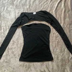 Svart tubtopp från shein med avtagbara ärmar XS  - Svart tubtopp i stretchigt material med avtagbara långärmade boleroärmar. Toppen är tight och slät, perfekt för en trendig look. Materialet är 80% polyamid och 20% elastan vilket gör den mjuk och följsam.