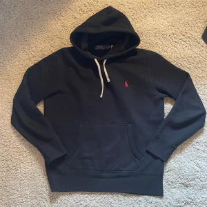 Svart hoodie från Polo Ralph Lauren - Säljer en Svart Ralph lauren hoddie i nytt skick. Tröjan är riktigt stilren och är väldigt varm. Snyggt nu under våren och passar även till sommaren. Nypris på denna är cirka 2100 och denna är rätt så ny🤩