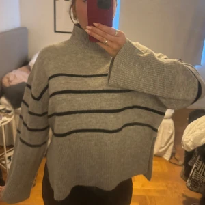 Grå randig stickad tröja  - säljer denna randliga stickade tröjan med en slits på båda sidor. skriv vid frågor