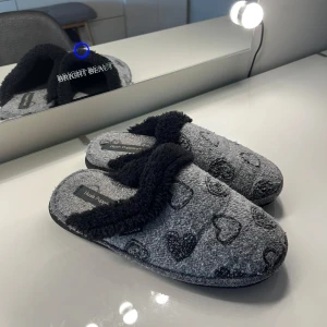 tofflor med hjärtmönster från Hush Puppies - Mysiga grå tofflor från Hush Puppies med ett sött hjärtmönster. De har en mjuk, fluffig insida och en stabil sula. Perfekta för att hålla fötterna varma och bekväma hemma.