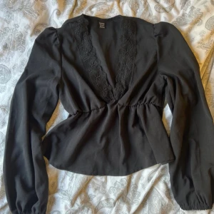 Svart blus - Svart blus med söt spets detalj urringning. 