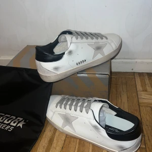 Golden goose - Golden Goose Superstar sneakers i storlek 43, modell Black Tail. Vit läderbas, grå stjärndetalj, svarta hälpartier och en vintageinspirerad sliten finish. Nästan nya, nyligen fått dem men de passade inte. Finns att hämta i Göteborg. Nypris: 6,800 kr.