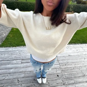 Vit stickad tröja - Säljer en stilren vit stickad tröja med trekvartsärm. Tröjan är croppad och har en ribbad nederkant som ger en snygg passform. Perfekt för en avslappnad look.