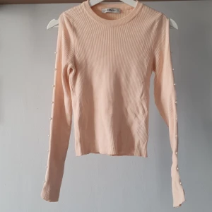 Rosa ribbad tröja från Zara - Rosa ribbad tröja från Zara med långa ärmar och dekorativa pärlor längs ärmarna. Tröjan är i ett mjukt och bekvämt material. Sparsamt använd! 💗 Ärmarna har öppna partier runt pärlorna så tröjan är riktigt snygg på (se bild 5)