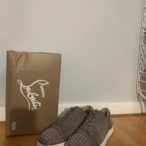 Gråa sneakers med nitar från Christian Louboutin - Gråa Christian Louboutin med nitar och den ikoniska röda sulan. OBS !! ALLT OG INGÅR, pris kan diskuteras vid snabb affär