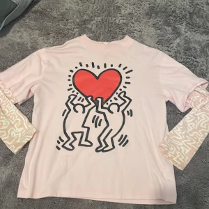 Rosa långärmad tröja med Keith Haring-design - Säljer en rosa t-shirt med inbyggda långa ärmar. Kommer från HM med Keith Haring design. Endast använd ett fåtal gånger, storlek 146-152