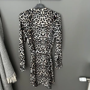 Leopardmönstrad klänning från Pieces - Snygg leopardmönstrad klänning från Pieces med långa ärmar och knytning i midjan. Perfekt för att sticka ut med ett djärvt mönster. Klänningen har en smickrande passform och är tillverkad i ett mjukt material.
