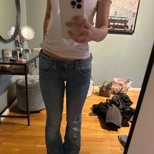 Blå bootcut jeans - Snygga blå bootcut jeans med låg midja. Perfekta för en avslappnad stil. Klassisk femficksdesign och dragkedja fram.