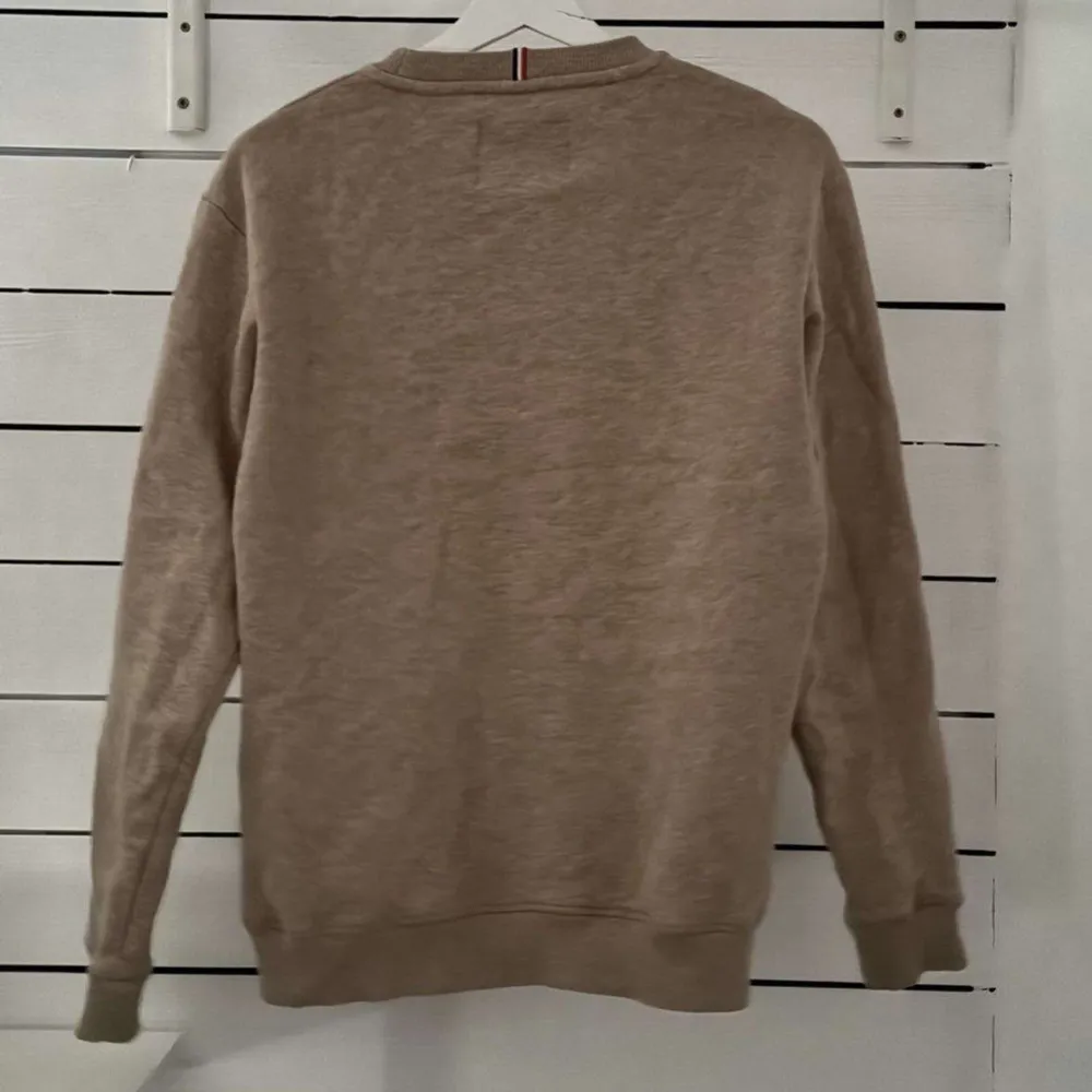 Säljer en stilren beige sweatshirt från Les Deux med svart text på bröstet. Tröjan har långa ärmar och ribbade muddar vid ärmslut och nederkant. Perfekt för en avslappnad stil.. Neuletakit & Villapaidat.