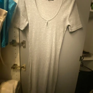 Grå klånning - Basic, super fin klänning från BikBok som ej säljs längre. Köpt för ett par år sedan och knappt använd. Passar till allt, perfekt till sommaren😍☀️Den är även sydd (se bild 2) för att inte vara super v-ringad :)