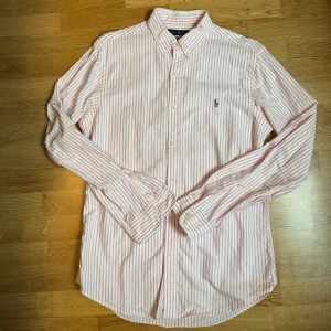 Ralph Lauren Skjorta - Tjena! Säljer nu min snygga rosa randiga Skjorta från Ralph Lauren som är perfekt nu för sommaren, skjortan är köpt för 1800! Skicket på skjortan är 9/10 som ny! Skjortan är i storlek M slimfit. Vid fler bilder/frågor är de bara att höra av sig, Pris kan diskuteras vid snabb affär!!