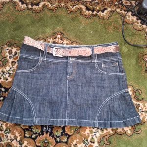 Jeanskjol med glittrigt bälte - Snygg jeanskjol med ett glittrigt bälte som ger en extra touch. Kjolen har fickor både fram och bak samt dekorativa sömmar. Perfekt för en trendig look!