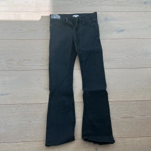 Svarta bootcut jeans från Gina Tricot - Snygga svarta bootcut jeans från Gina Tricot. De har en klassisk femficksdesign med dekorativa sömmar och en knappdetalj på bakfickan. Perfekta för en stilren look.