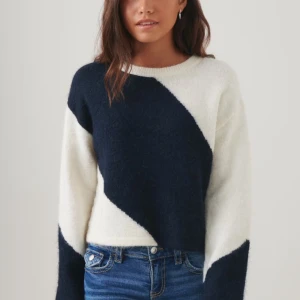 Vit och blå stickad tröja - Säljer en snygg stickad tröja i vit och mörkblå med ett diagonalt mönster. Tröjan har långa ärmar och en rund halsringning. Använt en gång.