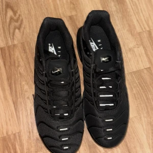 Svarta Nike Air Max sneakers - Snygga svarta Nike Air Max sneakers med en stilren design och synliga luftkuddar i sulan. Skorna har snörning och en rund tå, vilket ger en bekväm passform. Perfekta för både vardag och träning.