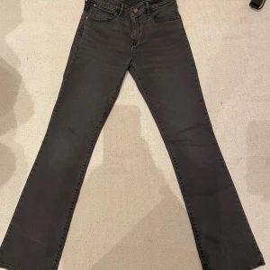 Mörka Wrangler Jeans - Svarta/ mörkgråa utsvängda Jeans. Ej använda. Midjemåttet: 33cm. Innerbenslängd: 82cm. W27 L32. Pris kan diskuteras!