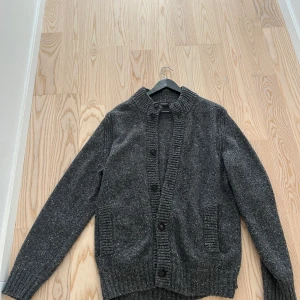 Grå kofta från MAERZ - Säljer en stilren grå kofta från ä MAERZ. Den har en ribbad krage och knäppning framtill med stora knappar. Perfekt för kyliga dagar. Nypris runt 2500. Säljs för att den köptes i fel storlek. Använd en gång endast. 