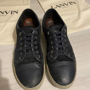 Mörkblå sneakers från Lanvin - Snygga mörkblå sneakers från Lanvin med snörning och rund tå. Skorna har en stilren design med en vit sula som ger en fin kontrast. Perfekta för en avslappnad men ändå elegant stil. Uk 7 = 41-42
