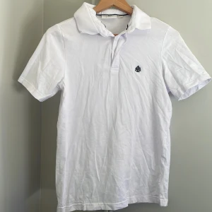 Vit kortärmad pikétröja - Säljer en klassisk vit kortärmad pikétröja med krage. Säljer för att den inte kommer till användning 