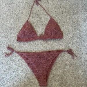 Gammelrosa virkad bikini - Snygg gammelrosa virkad bikini med knytband i både över- och underdel. Perfekt för en dag på stranden eller vid poolen. Den har en enkel och stilren design som ger en naturlig look. Virkat i material som fungerar att bada i och den torkar snabbt! Då det är justerbara band passar den XS-S med A eller B kupa! 