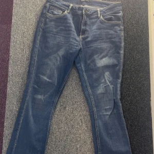 Blå jeans med strass från Texil - Säljer ett par klassiska blå jeans med fina rhinestones från Texil. De har en normal passform med snygga detaljer vid fickorna. Perfekta för en avslappnad men fräck stil.