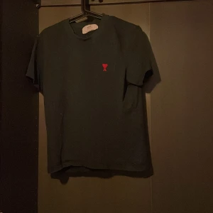 Olivgrön t-shirt från Ami Alexandre Mattiussi - Snygg svart t-shirt från Ami Alexandre Mattiussi med ett rött broderat hjärta och bokstaven A på bröstet. Perfekt för en stilren look.