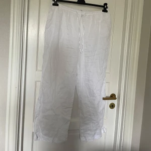 Vita linnebyxor med snörning - Säljer ett par vita linnebyxor med snörning i midjan. Byxorna har en loose passform och är perfekta för varma dagar. De är tillverkade i ett lätt och luftigt material som ger en skön känsla.