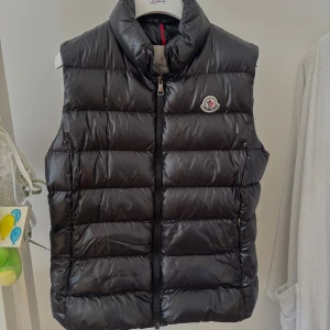 Moncler väst - Jag säljer nu min moncler väst , köpt år 2021. Mycket bra skick då den knappt kommit till användning. Jag är 158cm och passar vanligtvis i storlek S/M. Västen kommer såklart med tillhörande klädpåse samt galje. Äktheten kan verifieras med RFID chip och QR-kod. Inköpspris: 5000kr. 