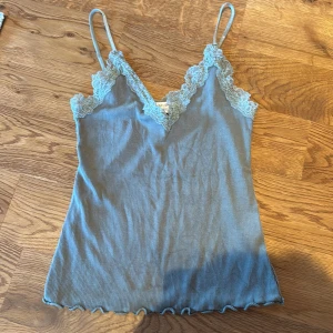 Grön ribbad linnetopp från Amisu - Säljer en söt grön ribbad linnetopp från Amisu med spetsdetaljer vid halsringningen och justerbara axelband. Perfekt för en avslappnad look och perfekt till sommaren. Hur gärna av er vid funderingar, pris går att diskutera💕