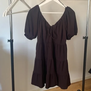 Brun klänning från Bik Bok - Säljer en brun klänning från Bik Bok med korta puffärmar och knytning framtill. 