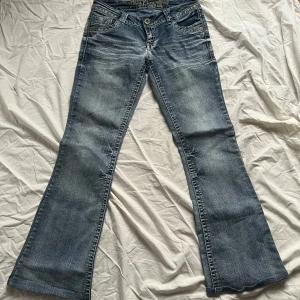 Blå bootcut jeans med broderade bakfickor - Snygga blå lågmidjade bootcut jeans med broderade detaljer på bakfickorna. 