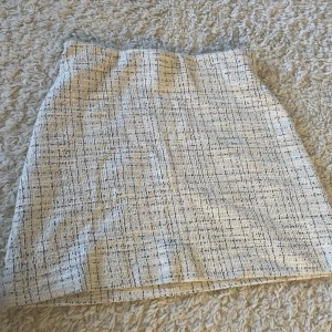 Vit rutig kjol från Kappahl - Snygg vit rutig kjol från Kappahl i en klassisk stil. Perfekt för en stilren look. Kjolen har en kort längd och är gjord i ett bekvämt material. Endast använd 1 gång 