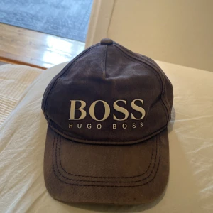 Blå keps från Hugo Boss - Snygg Blå keps från Hugo Boss med justerbart spänne baktill. Kepsen har en tydlig logotyp framtill och är perfekt för en stilren look. Passar bra till både vardag och avslappnade tillfällen. Lite liten i huvud passformen men den funkar om man justerar bandet. Kepsen har solblekning så ja kan sälja den för mindre