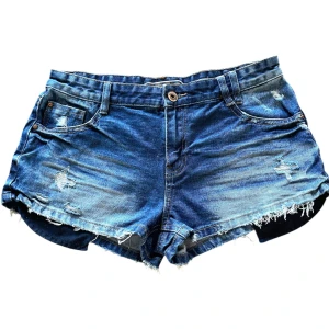 Blå jeansshorts med slitningar - Fina lowwaist jeansshorts med slitningar på fickorna och benen perfekta för sommaren! Fickorna sticker ut lite men dom går att stoppa in!💕                                                                           Midja mätt platt: 39cm                                                   Grenen: 24,5cm                                                            Pris går alltid att diskuteras💕