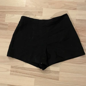 Svarta shorts - Snygga svarta shorts med en klassisk design. Perfekta för en stilren look. De har en enkel passform och är tillverkade i ett bekvämt material. Dragkedja i sidan, låtsasfickor på baken.