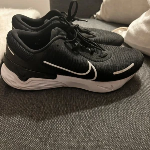 Svarta Nike sneakers - Säljer ett par svarta Nike sneakers med vit sula och klassisk Nike-logga i vitt. Skorna har snörning och en bekväm passform, perfekta för träning eller vardagsbruk.